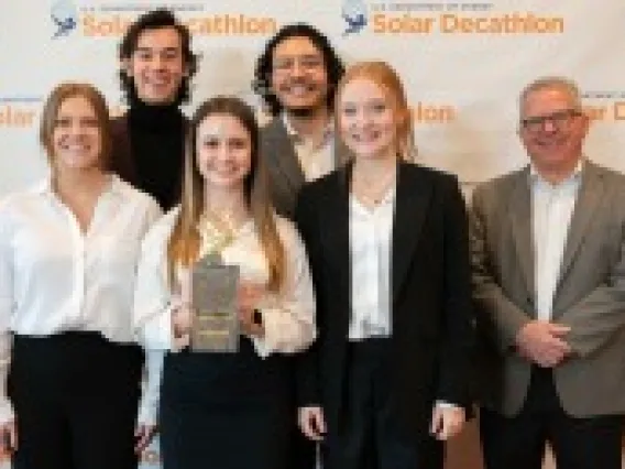 six people standing for a group photo with one holding an award