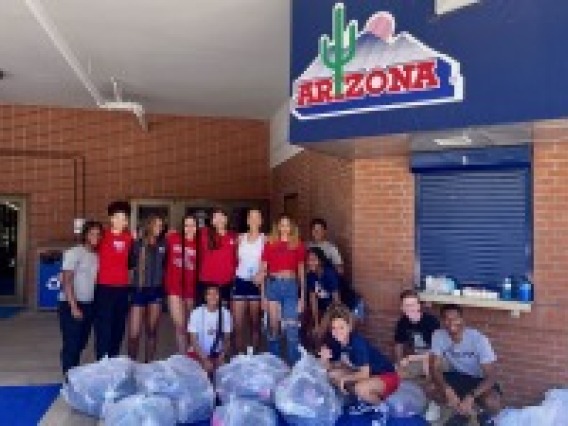 students posing with several bags of donated shoes