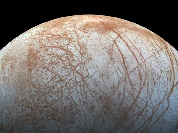 Illustration of Jupiter and its moon Europa in space. Jupiter, shown on the right, dominates the image with its swirling bands of clouds and large size. Europa, smaller and icy, appears in the foreground on the left, with a smooth, bright surface and visible line-like cracks. The blackness of space serves as the background.