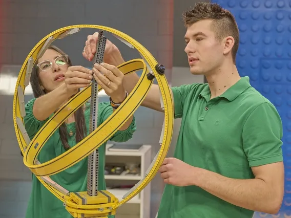 two people building a large structure with LEGO bricks