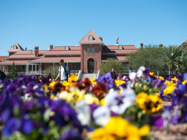 Old Main in the background, with purple, yellow, white and red flowers in the foreground
