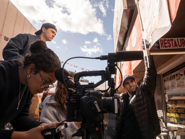 Film students surround a camera and film a scene outside of a restaurant.