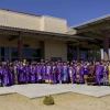 a group of graduates, mostly in purple caps and gowns, posing for a group photo at Tohono O'odham Community College