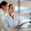 Two scientists in lab coats examine data